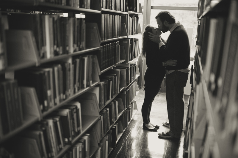 A bride and groom kiss in the stacks at Joe Paterno Library during their engagement session the week of their wedding.