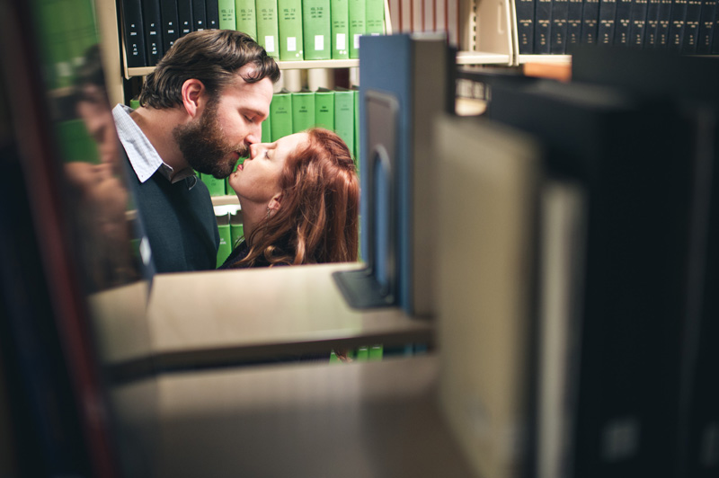 A couple kiss in the stacks of Joe Paterno Library on the University Park campus of PSU while their wedding photographer shoots through the books.