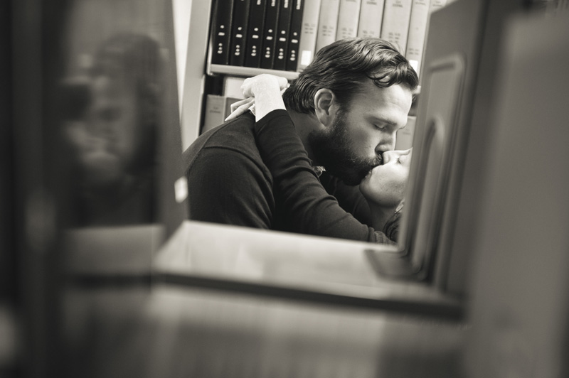 An engagement session in the library in State College produces a beautiful shot of a kiss reflected in the books on the shelves.
