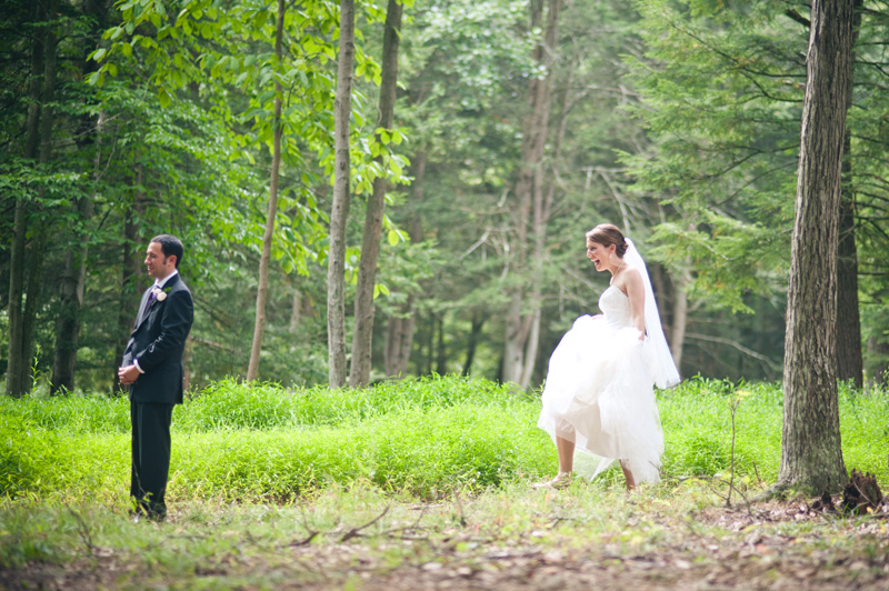 A bride sneaks up on the groom before their first look in the trees at the McCann School of art.